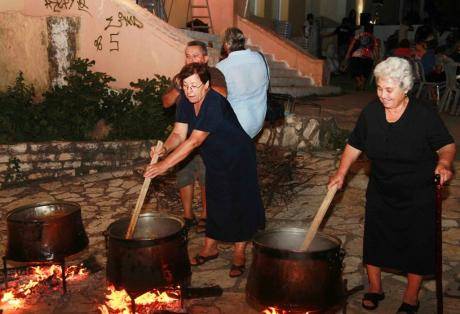 Euboea, Oxilithos Festival - Gastronomy Tours Woman mixing with wooden rods in a bronze cauldrons at Oxilithos Festival, Euboea, Greece, by night